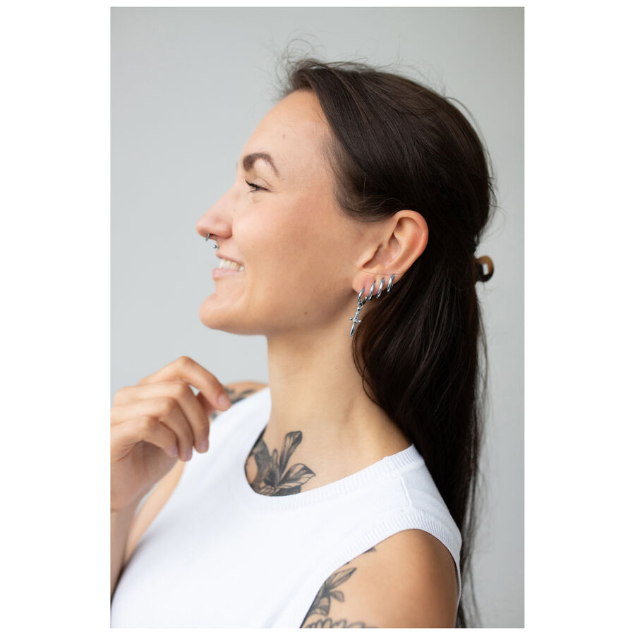Donna con lunghi capelli scuri indossa orecchini Little Sword Hoops in argento su sfondo chiaro