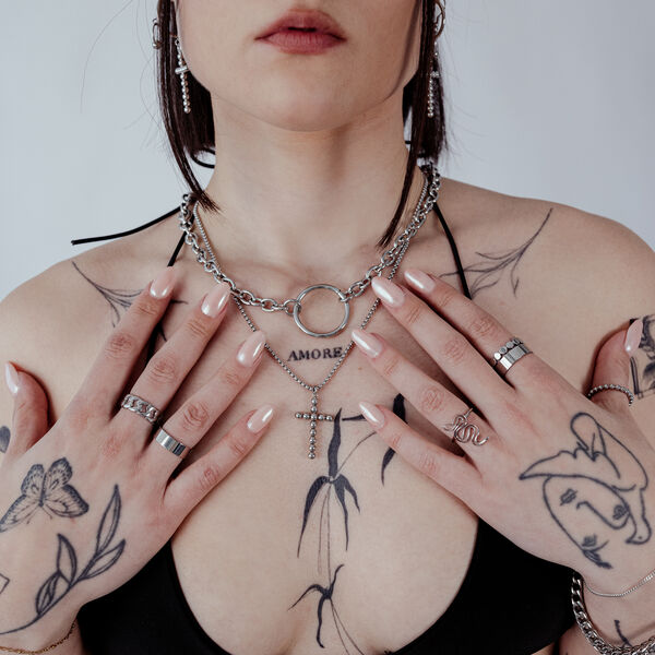 Mujer con Collar Wildcat O de acero quirúrgico, tatuajes y anillos