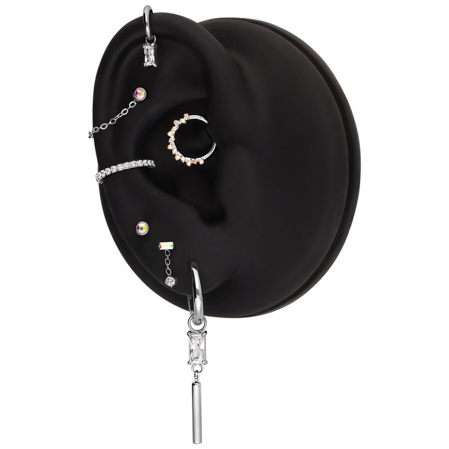 Schwarzes Ohrmodell mit verschiedenen Piercings und Creolen in Silber und Kristall.