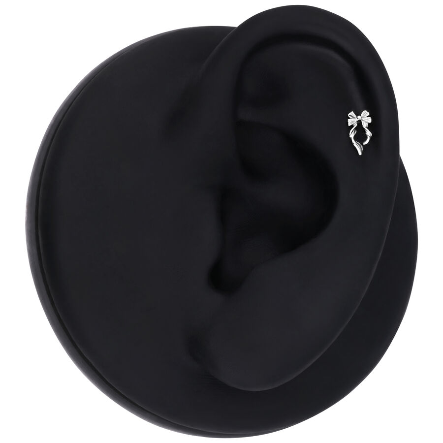 Modello di orecchio nero con piercing a forma di fiocco in argento su sfondo nero