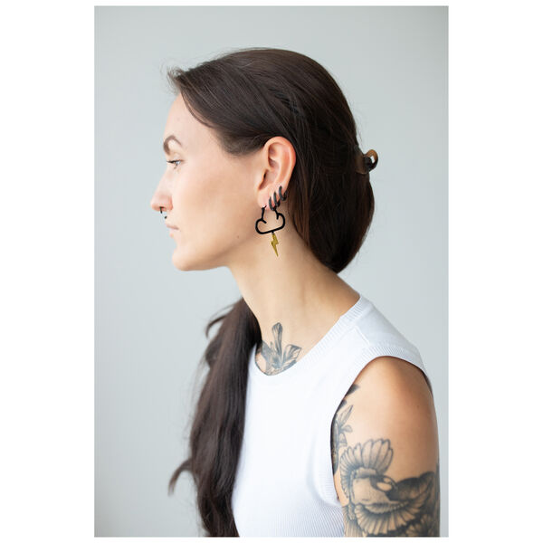 Mujer con cabello largo y oscuro lleva pendientes negros y dorados en forma de nube