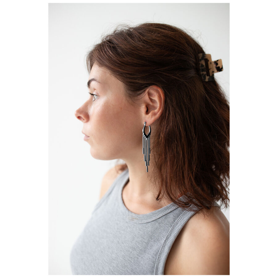 Donna con capelli castani indossa cerchi Snakechain neri davanti a sfondo bianco