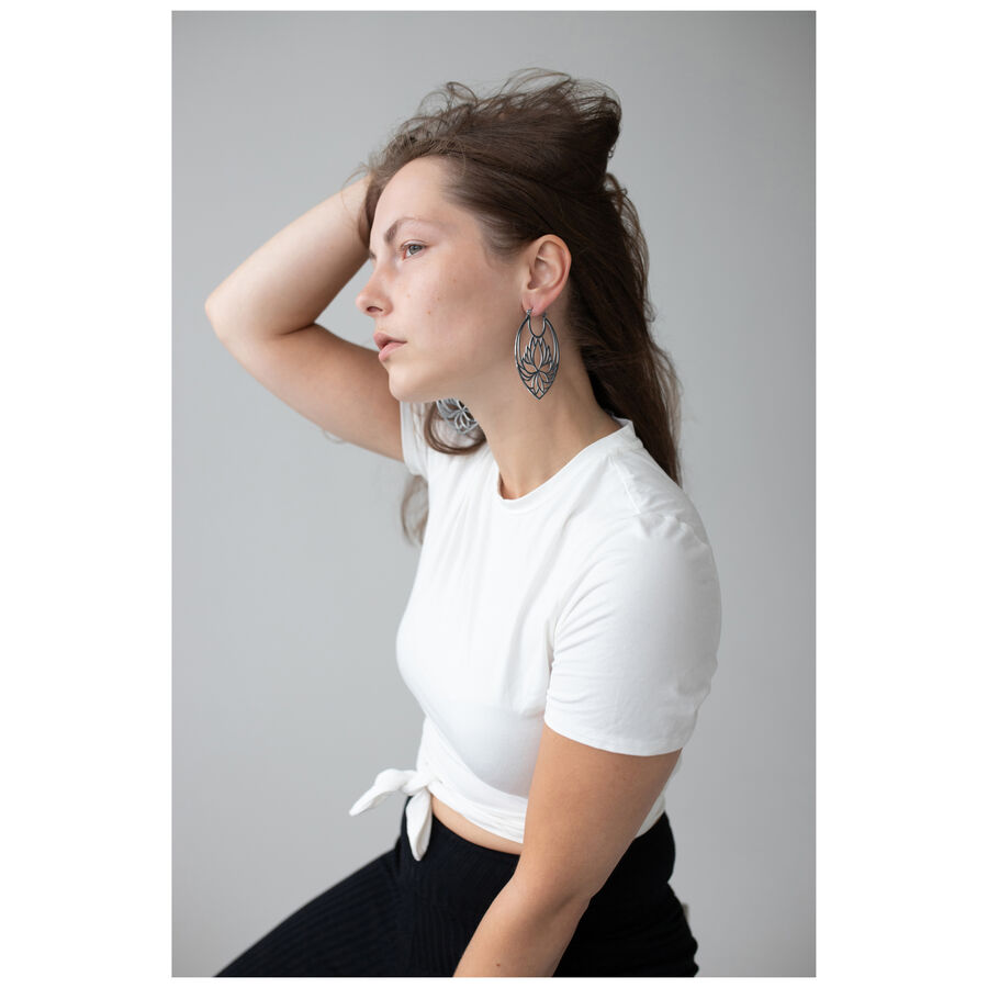 Donna con orecchini Lotus Hoops in acciaio inossidabile nero e argento su sfondo grigio