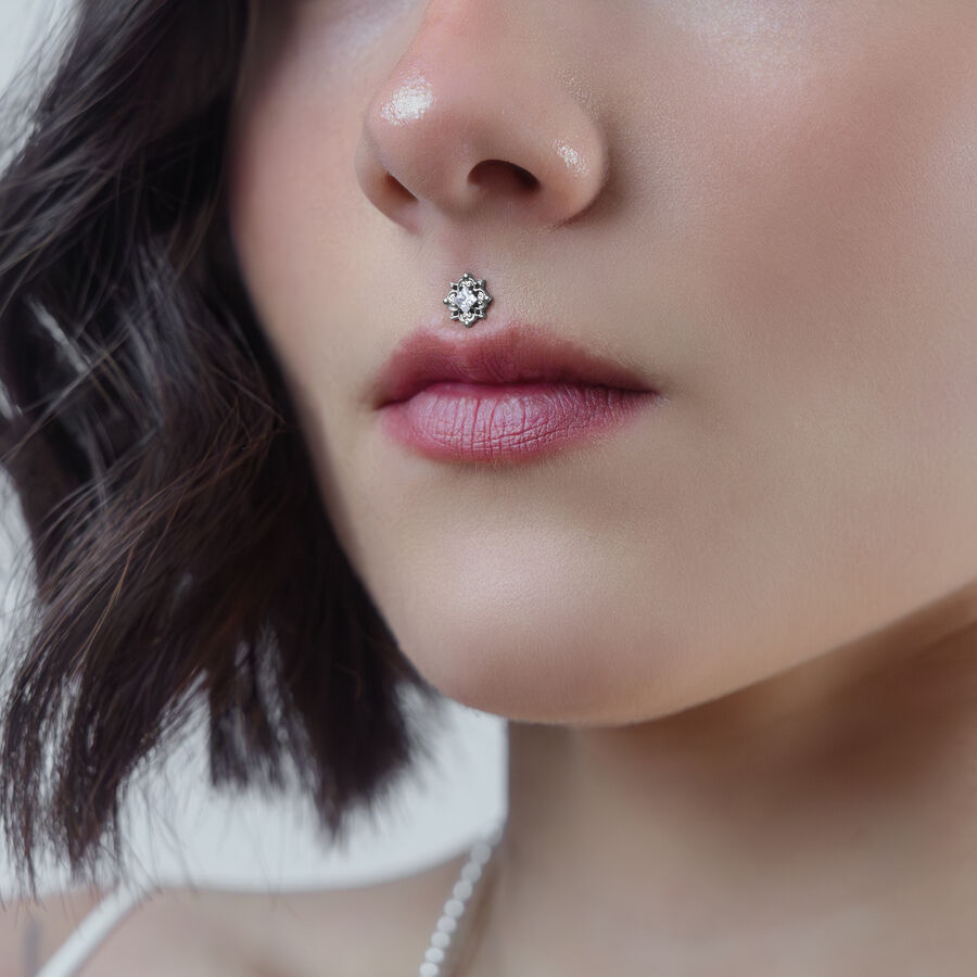 Primo piano di un cristallo per piercing in argento su un piercing Medusa di una donna su sfondo neutro