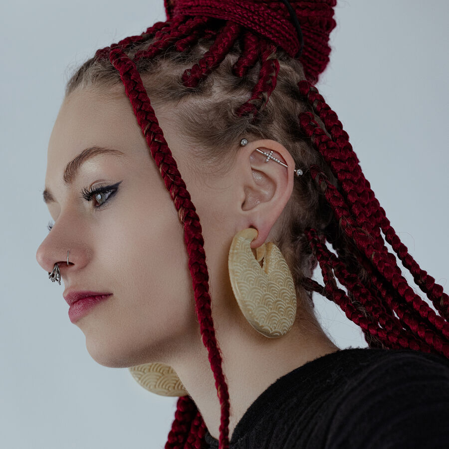 Persona con trecce rosse indossa grandi pesi per orecchie Waves in legno