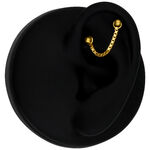 Catena piercing in oro 585 su un orecchio nero su sfondo nero