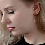 Frau mit mehreren Piercings, darunter ein goldener Kristall-Piercingaufsatz im Ohr.