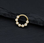 Anello piercing dorato con pietre di moissanite scintillanti su sfondo nero