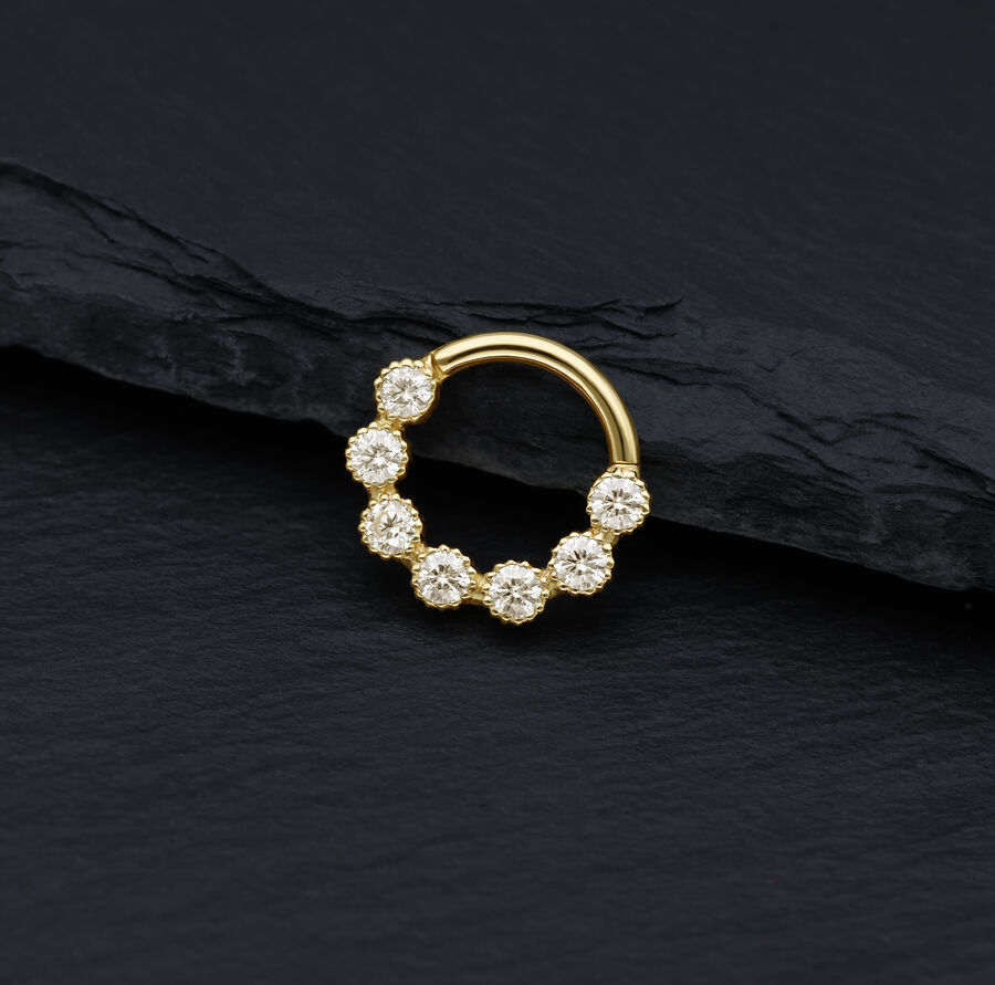 Anello piercing dorato con pietre di moissanite scintillanti su sfondo nero
