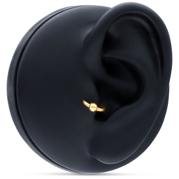 Aro de bola de presión de oro en piercing de oreja sobre fondo negro