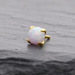 Runder 14K Goldaufsatz mit synthetischem Opal auf grauem Hintergrund
