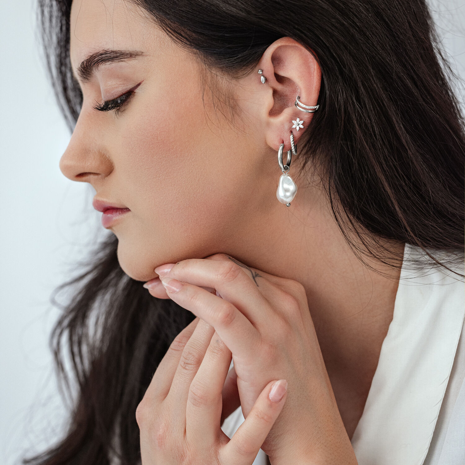 Elegante Barock-Perlen Creolen im Silber-Look Seitenansicht einer Frau mit Barock-Perlen Creolen und weiteren Ohrringen auf hellem Hintergrund