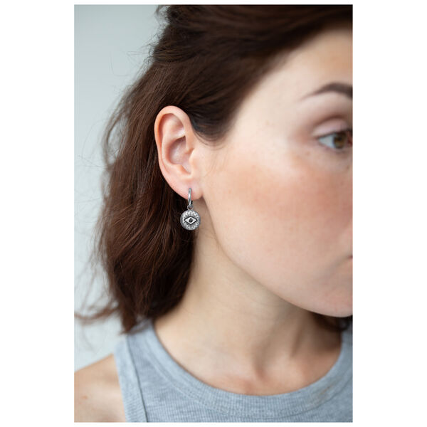 Mujer con aros plateados con motivo de ojo, vista lateral