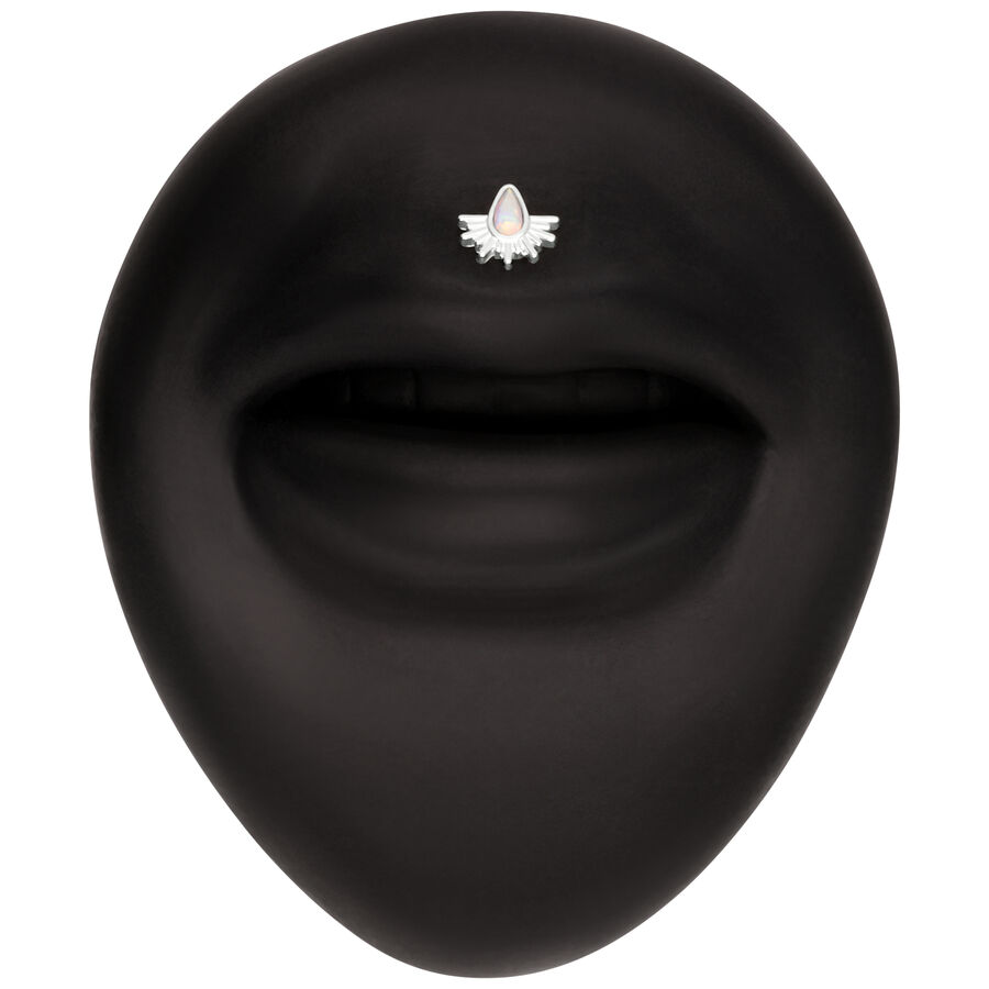 Sfondo nero con un piccolo accessorio bianco a forma di raggi solari, decorato con una pietra opalescente.