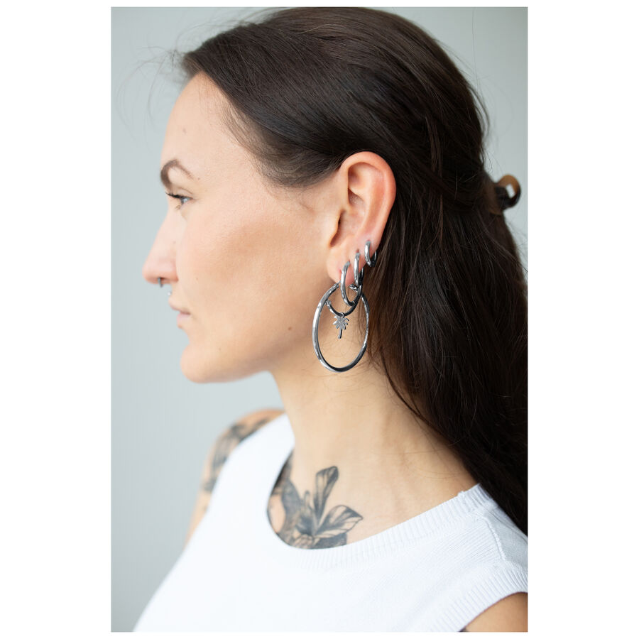 Mujer con cabello largo y oscuro lleva grandes aros de plata