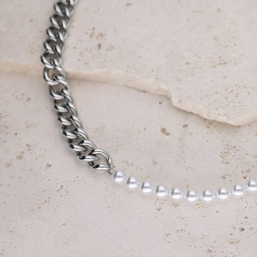 Collana a maglie d'argento combinata con perle sintetiche su sfondo di pietra chiara