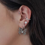 Orecchini Little Butterfly Hoops in argento sull'orecchio di una donna, con altri orecchini a perno