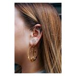 Piercings de oro con ancla y cadena, usados en la oreja de una mujer.