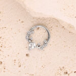 Silberner Piercing-Ring mit Kristallen auf hellem Stein