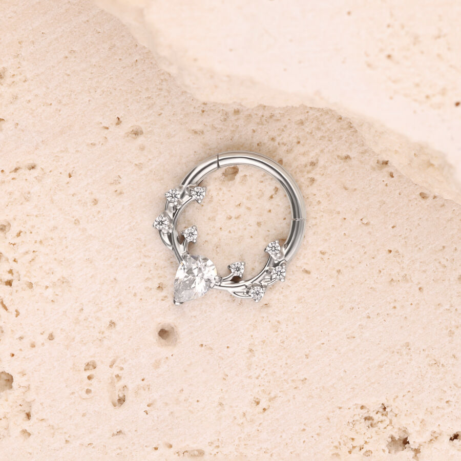 Silberner Piercing-Ring mit Kristallen auf hellem Stein