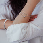 Bracciale a doppio filo in argento con ciondolo a cuore sul braccio di una persona con abbigliamento bianco