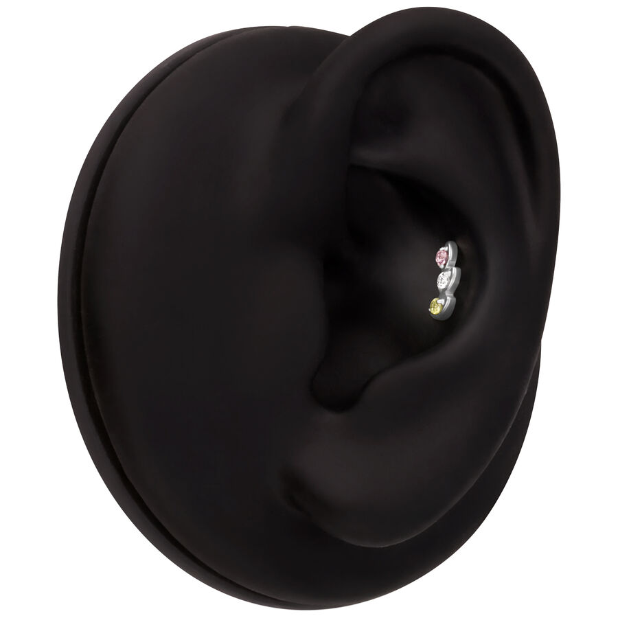 Modello di orecchio nero con tre pietre scintillanti per piercing in argento, oro e rosa su sfondo nero