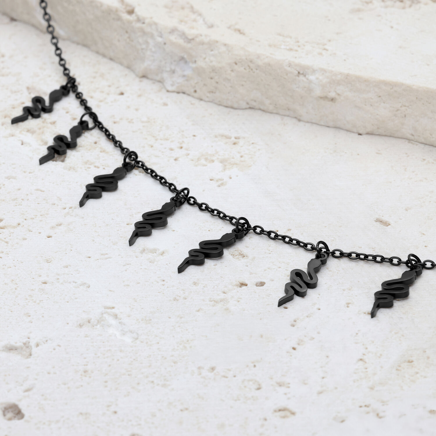 Schwarzes Snake Armband aus Chirurgenstahl Schwarzes Snake Armband mit verstellbarem Verschluss auf hellem Stein