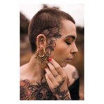 Persona con piercing Mandala Labret dorati e tatuaggi su viso e corpo
