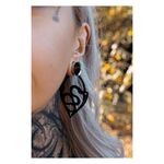 Primo piano di un orecchio con orecchini Snake Hoops neri, sfondo sfocato
