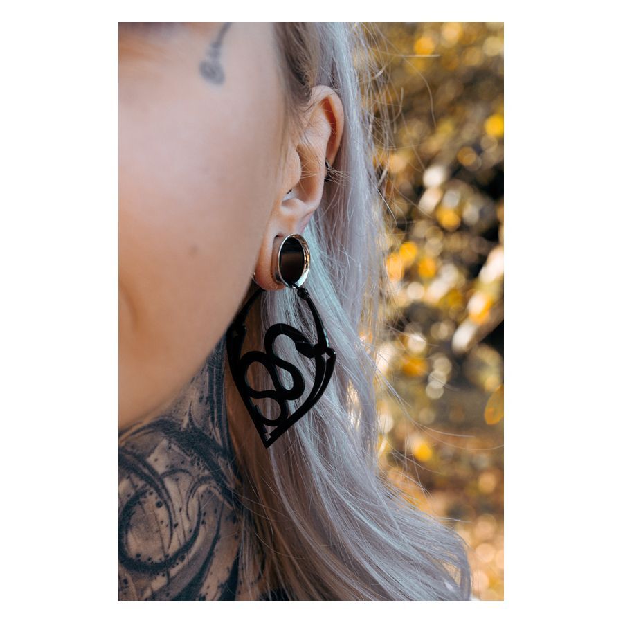 Primo piano di un orecchio con orecchini Snake Hoops neri, sfondo sfocato