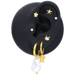 Modelo de oreja negra con aros dorados, perlas y adorno de estrella