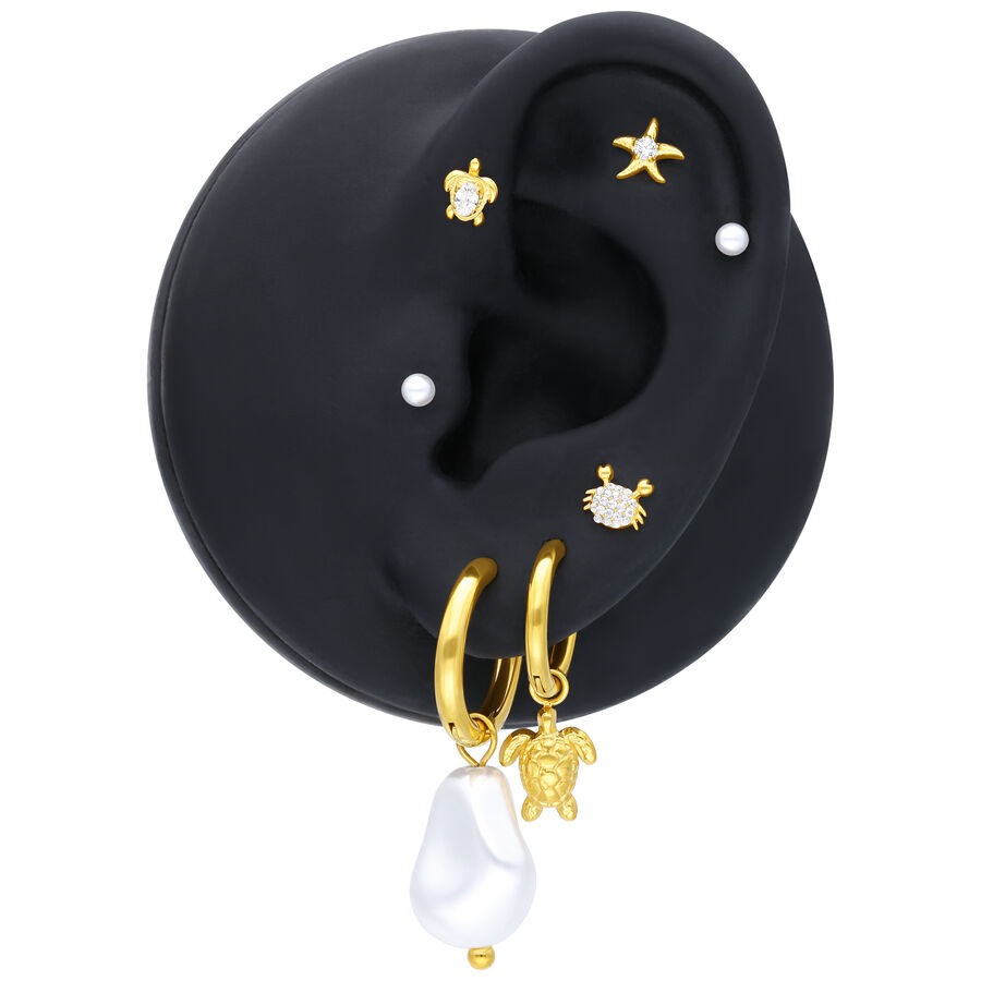 Modelo de oreja negra con aros dorados, perlas y adorno de estrella