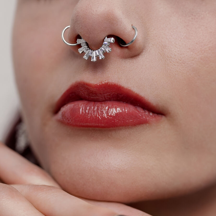 Primo piano di un clicker per setto in argento con cristalli in un naso, visibili labbra rosse