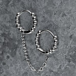 Orecchini doppio Huggie in argento con sfere e catena su sfondo grigio