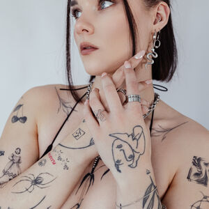 Eleganter Schlangenring aus Chirurgenstahl Person mit Schlangenring und Tattoos, trägt Schmuck auf weißem Hintergrund