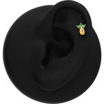 Aplique de piña dorada con hojas verdes en un display negro para oreja
