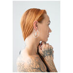 Mujer con pendientes de corazón de acero quirúrgico plateado, perfil lateral