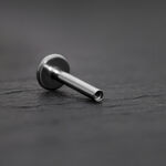 Labret de titanio plateado con rosca interna sobre fondo gris