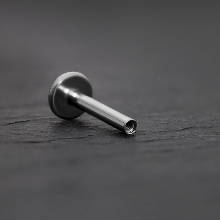 Labret de titanio plateado con rosca interna sobre fondo gris