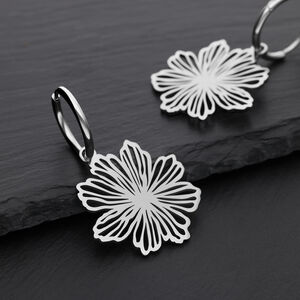 Elegante Blumen-Ohrringe aus Edelstahl Zwei silberne Ohrringe mit Blumenmuster auf schwarzem Hintergrund