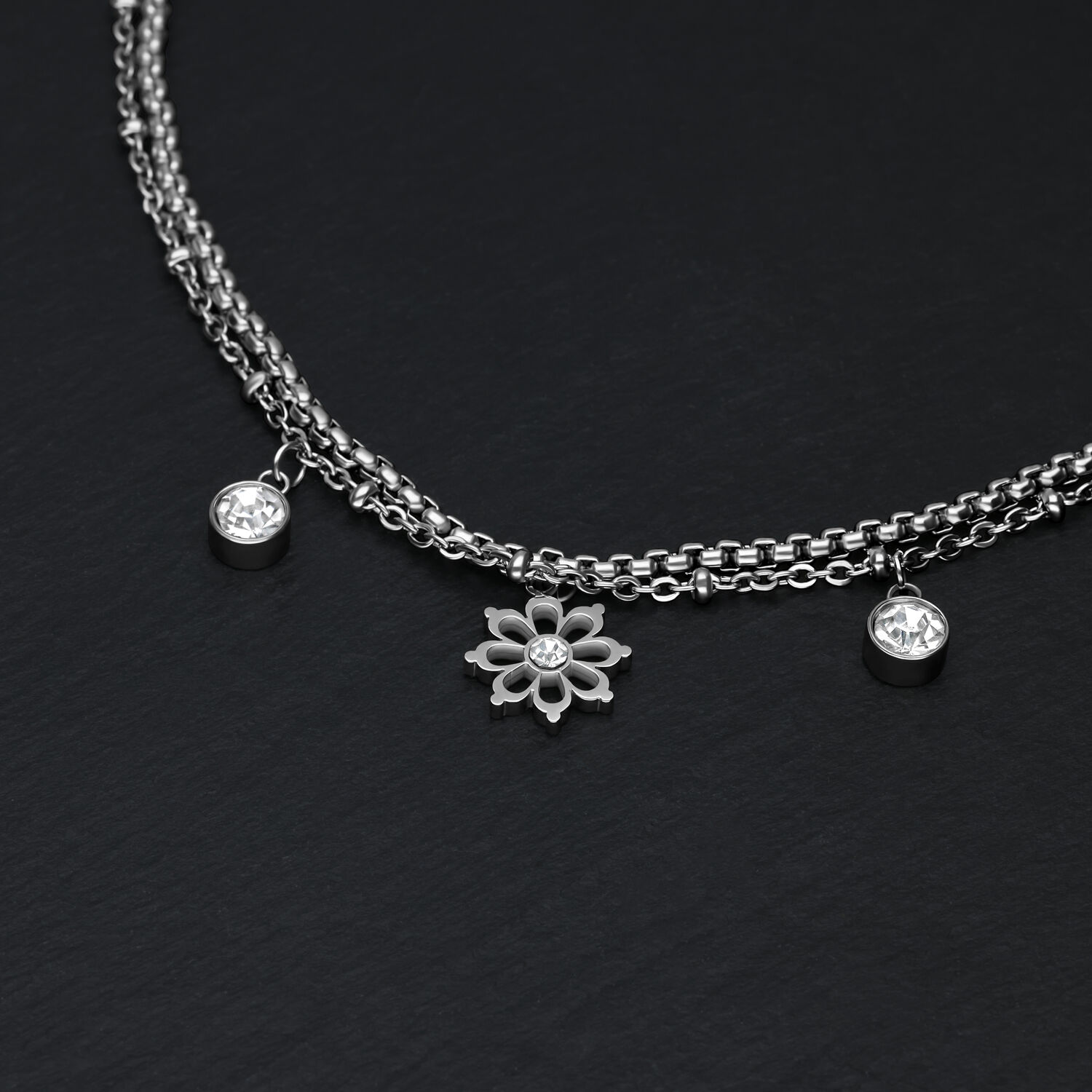 Little Floralis Armband in Silber mit Kristall Silbernes Armband auf schwarzem Hintergrund mit floralen Anhängern und Kristallen