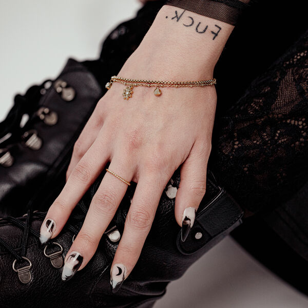 Mano con Little Floralis Pulsera en Oro sobre bota de cuero negra