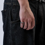 Mano con anello a catena argento, indossato su jeans scuri, primo piano