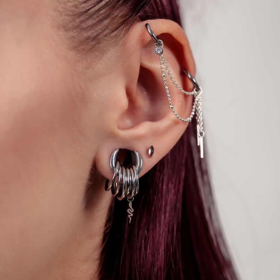 Primo piano di un orecchio con inserti piercing in argento e catene