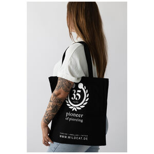 Schwarze Wildcat Baumwolltasche 'Bite Me' Frau trägt schwarze Baumwolltasche mit Wildcat-Logo und 'Bite Me'-Aufdruck