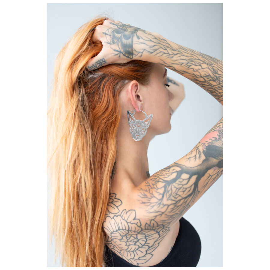 Mujer con cabello rojo lleva Sphynx Hoops plateados sobre fondo claro