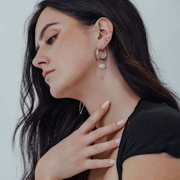 Donna con lunghi capelli scuri indossa Stone Hoops bianchi in acciaio chirurgico all'orecchio