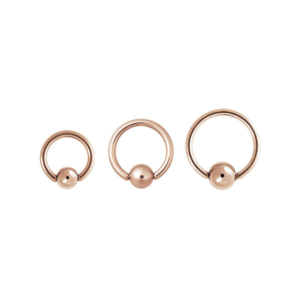 Tre anelli clip in oro rosa di diverse dimensioni su sfondo bianco