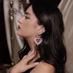 Mujer con pendientes Barbed Wire Sacred Heart, cabello negro, fondo elegante