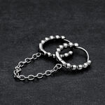 Due anelli piercing Huggie neri collegati con sfere su sfondo scuro